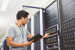 Telekom Mitarbeiter mit Tablet vor geöffnetem Rack